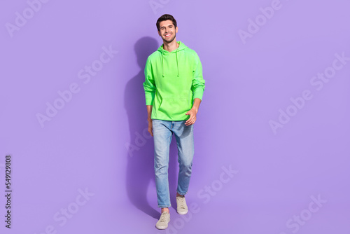 Full length size photo of young attractive stylish model man wear nice green pullover cheap jeans trendy sneakers isolated on purple color background © deagreez