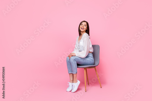 Full length photo of cute lovely lady sit armchair good mood dressed trendy clothes empty space isolated pink color background