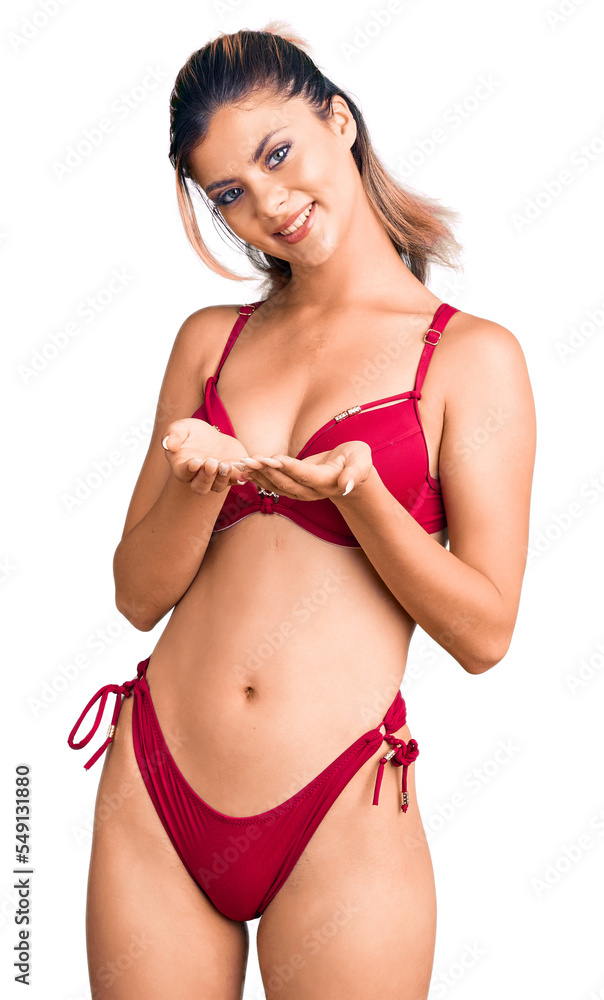 Young beautiful woman wearing bikini smiling with hands palms together receiving or giving gesture. hold and protection Young beautiful woman wearing bikini smiling with hands palms together receiving or giving gesture. hold and protection