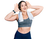 Young hispanic girl wearing sportswear and towel smiling cheerful playing peek a boo with hands showing face. surprised and exited