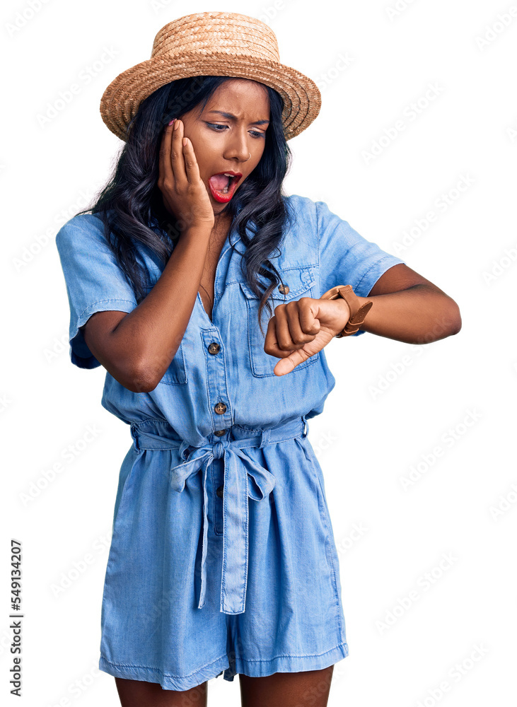 Young indian girl wearing summer hat looking at the watch time worried, afraid of getting late Young indian girl wearing summer hat looking at the watch time worried, afraid of getting late