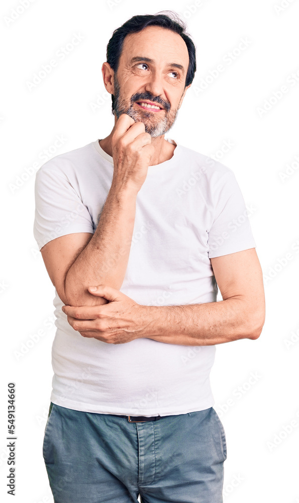 Middle age handsome man wearing casual t-shirt with hand on chin thinking about question, pensive expression. smiling and thoughtful face. doubt concept. Middle age handsome man wearing casual t-shirt with hand on chin thinking about question, pensive expression. smiling and thoughtful face. doubt concept.