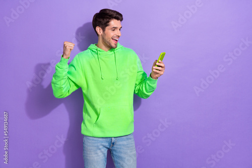 Fototapete Photo of impressed attractive guy with brunet hairdo dressed green hoodie hold l