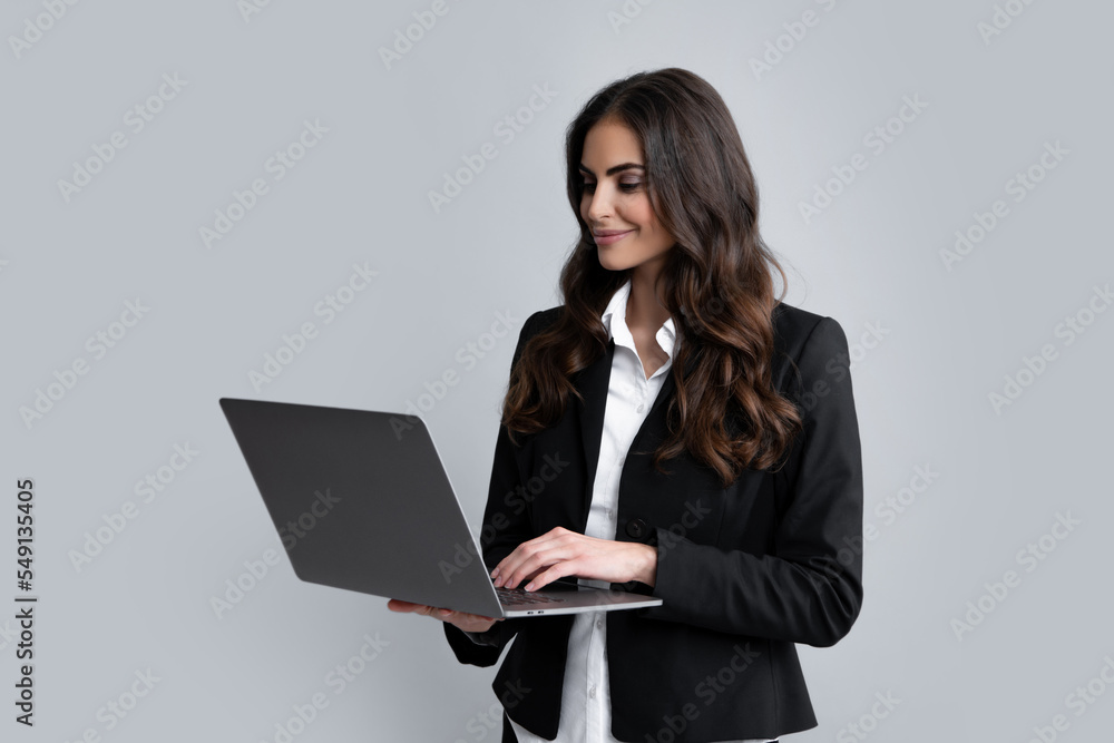 Portrait of positive cheerful ceo expert business woman work at laptop isolated over gray background. Secretary with laptop, studio portrait. Portrait of positive cheerful ceo expert business woman work at laptop isolated over gray background. Secretary with laptop, studio portrait.