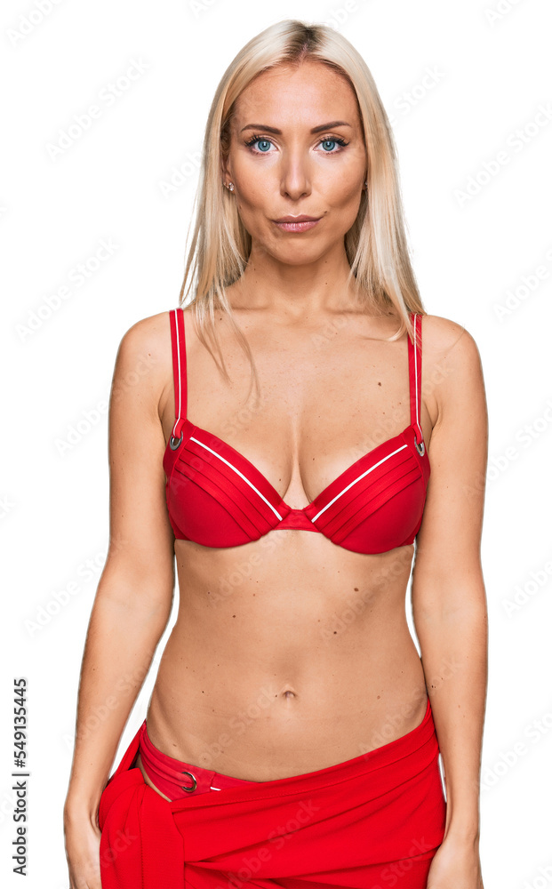 Young blonde woman wearing bikini with serious expression on face. simple and natural looking at the camera. Young blonde woman wearing bikini with serious expression on face. simple and natural looking at the camera.