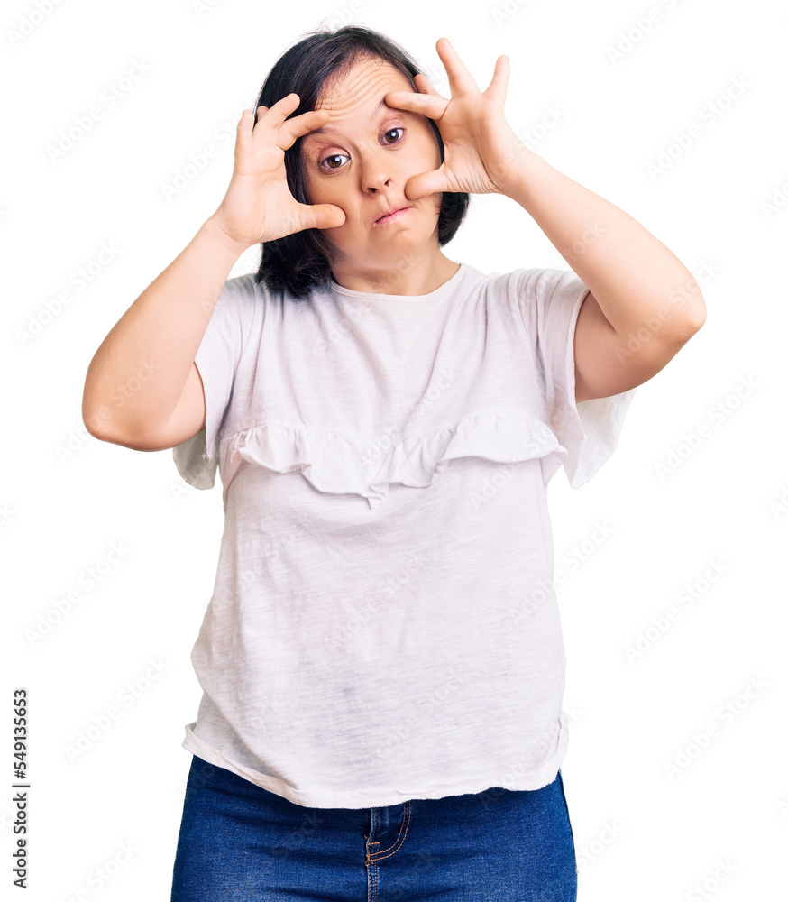 Brunette woman with down syndrome wearing casual white tshirt trying to open eyes with fingers, sleepy and tired for morning fatigue Brunette woman with down syndrome wearing casual white tshirt trying to open eyes with fingers, sleepy and tired for morning fatigue