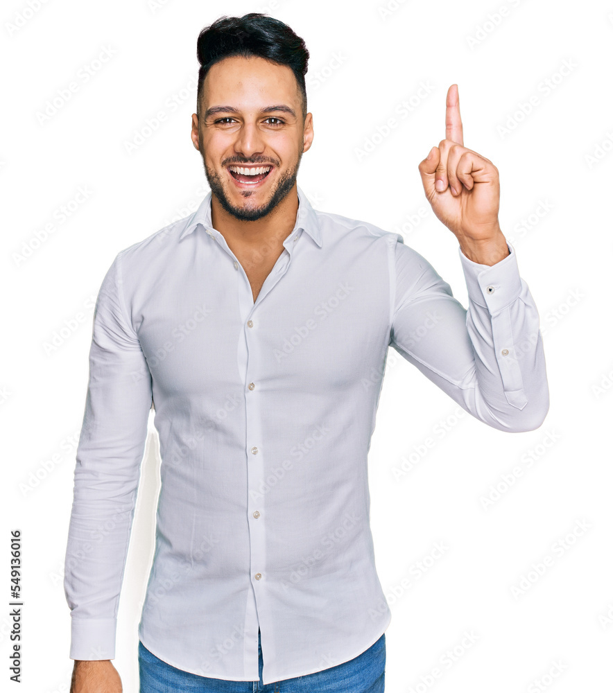 Young arab man wearing casual clothes pointing finger up with successful idea. exited and happy. number one. Young arab man wearing casual clothes pointing finger up with successful idea. exited and happy. number one.