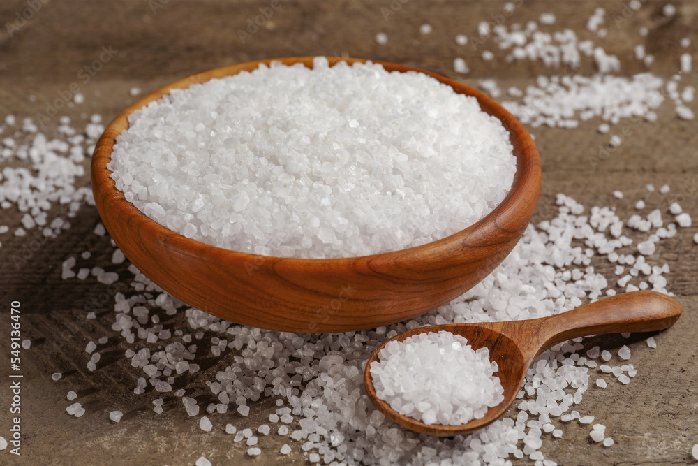 Bowl and spoon with natural sea salt on wooden table Bowl and spoon with natural sea salt on wooden table
