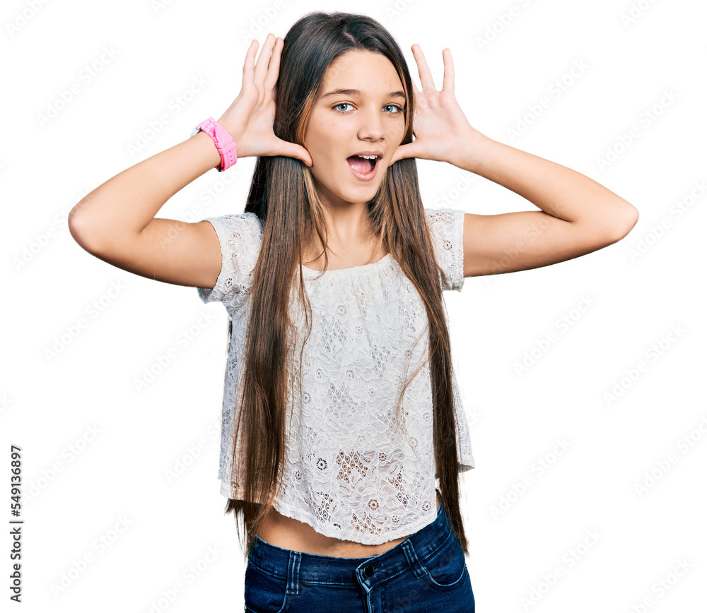 Young brunette girl with long hair wearing white shirt smiling cheerful playing peek a boo with hands showing face. surprised and exited Young brunette girl with long hair wearing white shirt smiling cheerful playing peek a boo with hands showing face. surprised and exited
