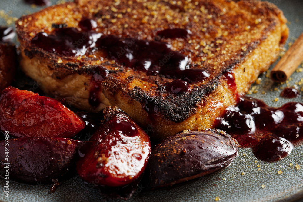 French toast with baked plums, served on a plate. Close up view.
