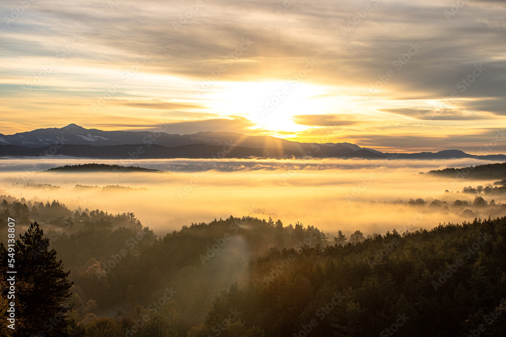 Fototapeta premium sunrise over a mountain below a misty valley 