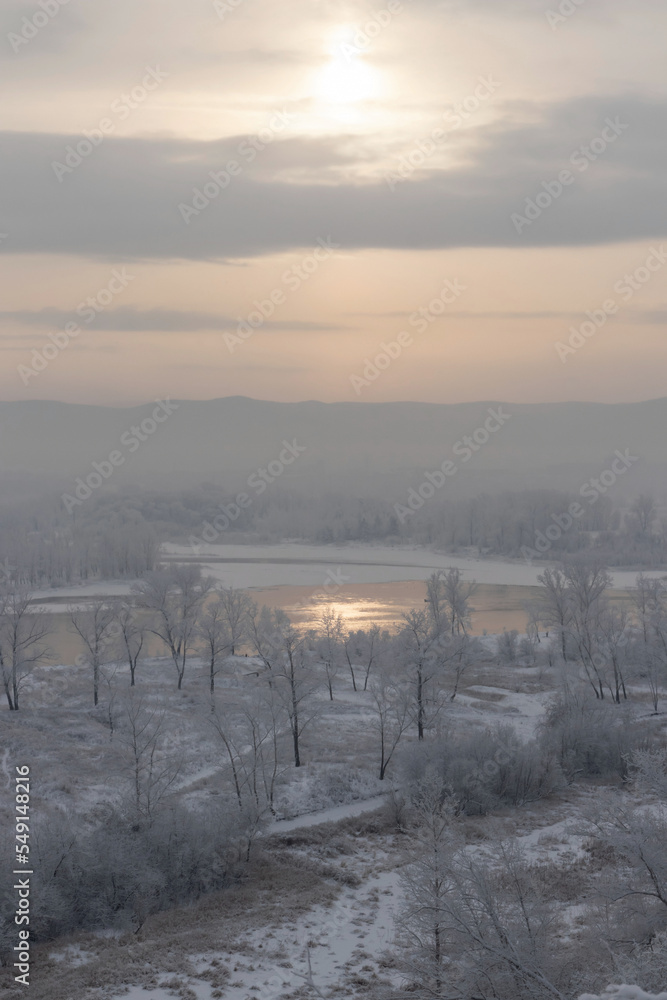 Winter landscape - view across the river to the opposite bank on a foggy winter day in the setting sun Winter landscape - view across the river to the opposite bank on a foggy winter day in the setting sun