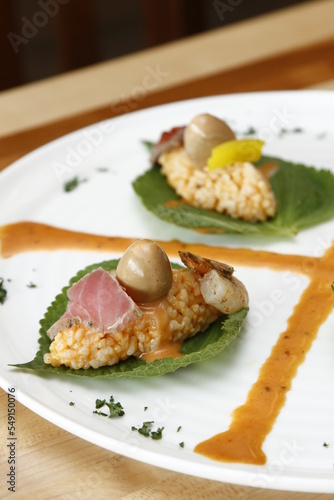 Appetizer made of rice shrimp, quail egg, salmon served on a leaf