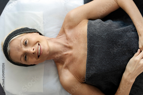 Top view of smiling senior woman laying at the couch after making an effective facial procedure