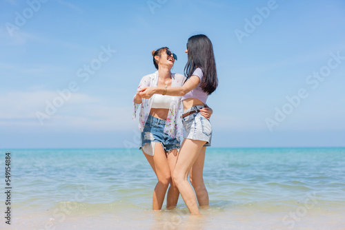 Two girlfriends hugging up and enjoying on the sea beach. A pair of girls in love cuddling on a tropical beach. romantic young lesbian couples in love and walking together on the beach.Concept of LGBT © kongga studio