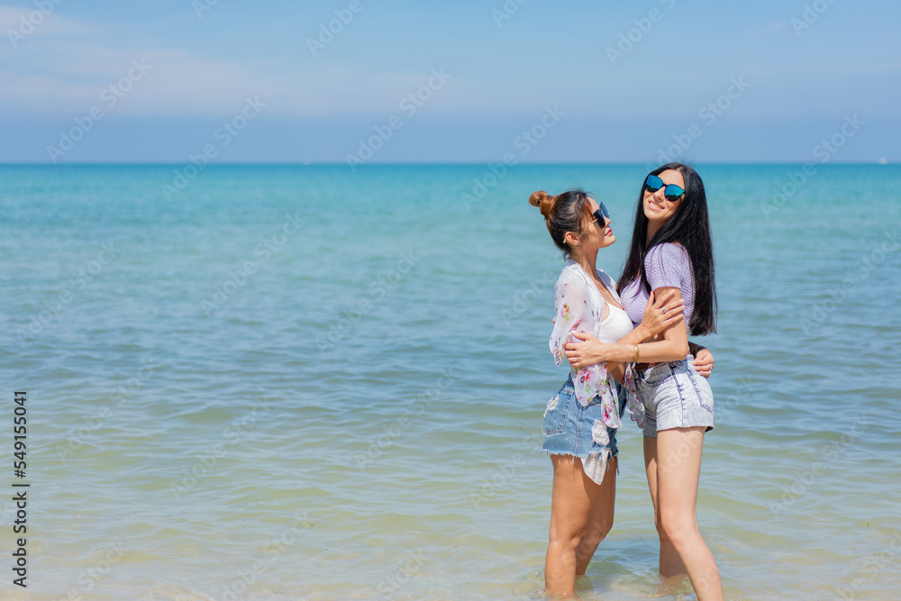 Two girlfriends hugging up and enjoying on the sea beach. A pair of girls in love cuddling on a tropical beach. romantic young lesbian couples in love and walking together on the beach.Concept of LGBT Two girlfriends hugging up and enjoying on the sea beach. A pair of girls in love cuddling on a tropical beach. romantic young lesbian couples in love and walking together on the beach.Concept of LGBT