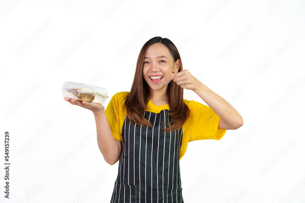 Holding Krapao (Thai food) box, Portrait of confident asian woman barista and food owner shop with yellow t-shirt and black apron standing on white background. Holding Krapao (Thai food) box, Portrait of confident asian woman barista and food owner shop with yellow t-shirt and black apron standing on white background.