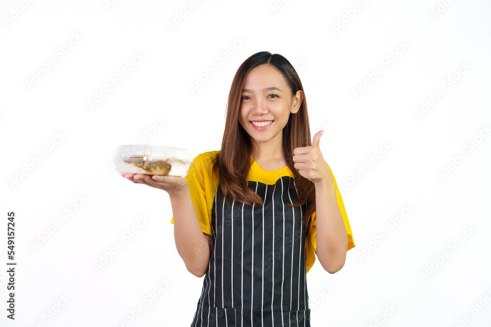 Holding Krapao (Thai food) box, Portrait of confident asian woman barista and food owner shop with yellow t-shirt and black apron standing on white background. Holding Krapao (Thai food) box, Portrait of confident asian woman barista and food owner shop with yellow t-shirt and black apron standing on white background.