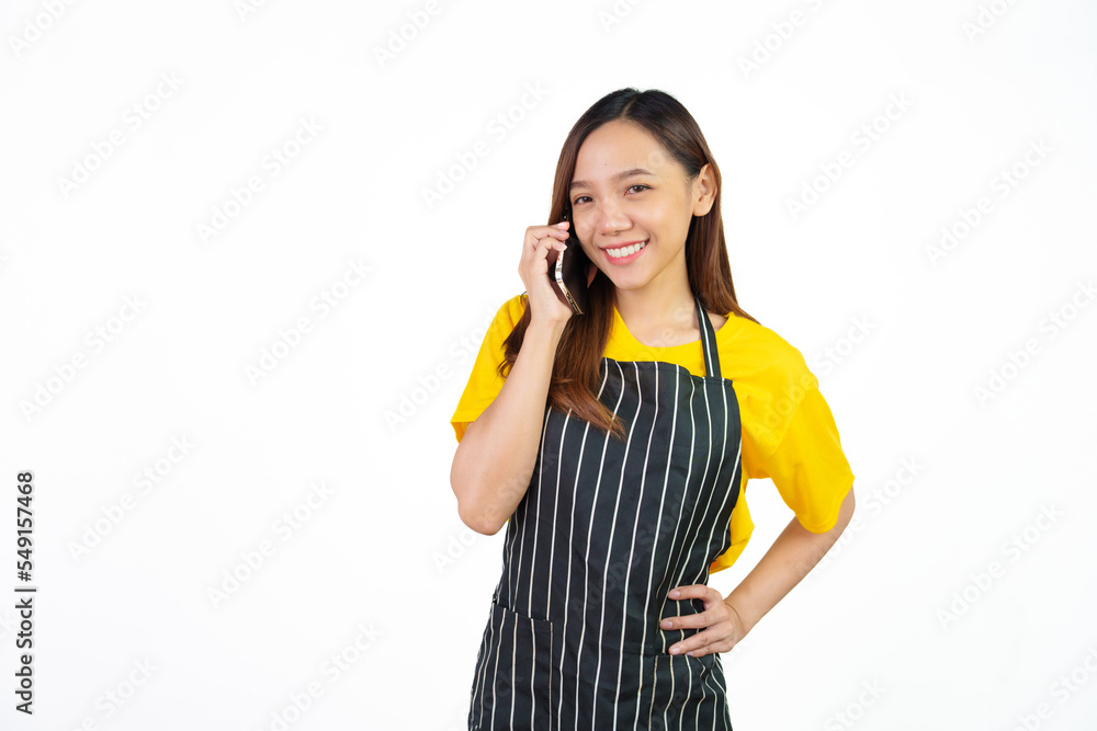 Talking or call mobile phone, Portrait of confident asian woman barista and food owner shop with yellow t-shirt and black apron standing on white background. Talking or call mobile phone, Portrait of confident asian woman barista and food owner shop with yellow t-shirt and black apron standing on white background.