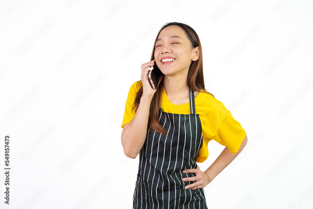 Talking or call mobile phone, Portrait of confident asian woman barista and food owner shop with yellow t-shirt and black apron standing on white background. Talking or call mobile phone, Portrait of confident asian woman barista and food owner shop with yellow t-shirt and black apron standing on white background.
