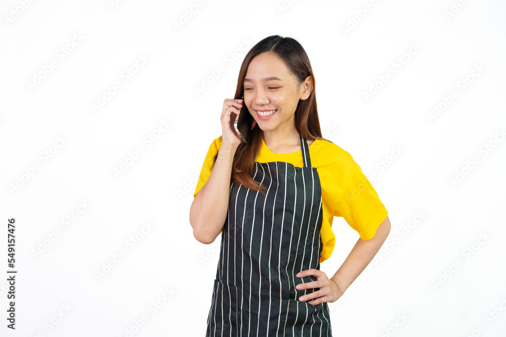 Talking or call mobile phone, Portrait of confident asian woman barista and food owner shop with yellow t-shirt and black apron standing on white background. Talking or call mobile phone, Portrait of confident asian woman barista and food owner shop with yellow t-shirt and black apron standing on white background.