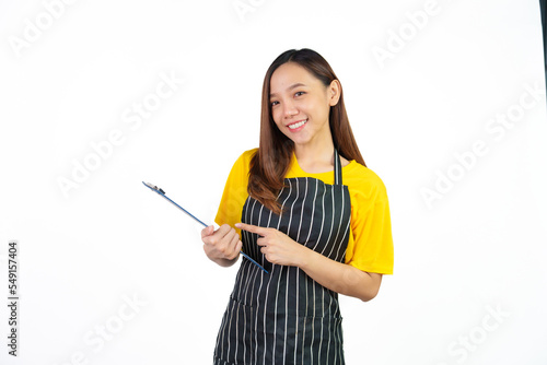 Holding menu on clipboard  Portrait of confident asian woman barista and food owner shop with yellow t-shirt and black apron standing on white background.