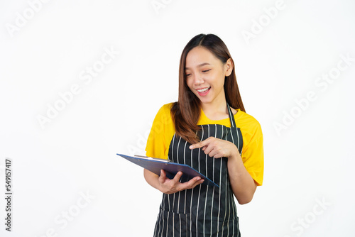 Holding menu on clipboard  Portrait of confident asian woman barista and food owner shop with yellow t-shirt and black apron standing on white background.