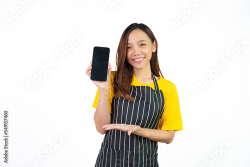 Showing blank screen mobile phone for display your ads  Portrait of confident asian woman barista and food owner shop with yellow t-shirt and black apron standing on white background.
