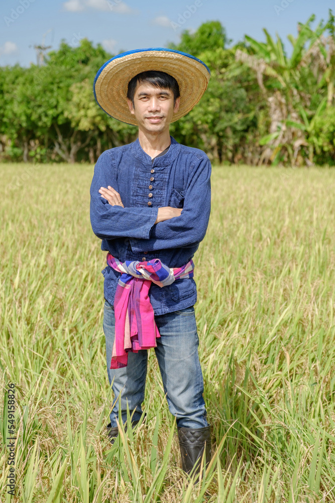 Asian male farmer wearing traditional blue dress standing with arms crossed at the farm