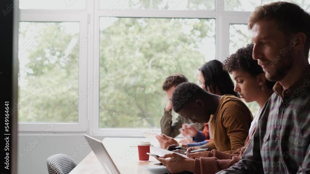 group of young people sitting at a table in a coworking center . group of young people sitting at a table in a coworking center .