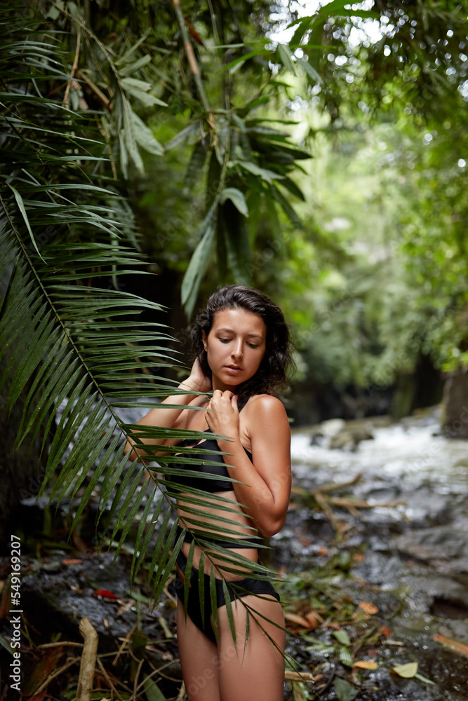 Portrait Young slender girl posing in the jungle hiding behind a palm leaf. Wildlife and a girl Portrait Young slender girl posing in the jungle hiding behind a palm leaf. Wildlife and a girl