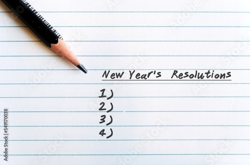 A pen on a lined nite paper, with text written NEW YEAR'S RESOLUTIONS and the blank list- concept of making determined resolutions to change in the next coming year