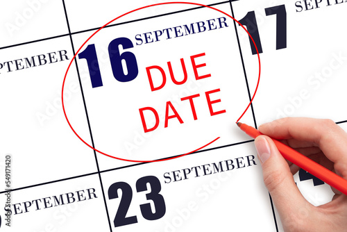 16th day of September. Hand writing text DUE DATE on calendar date September 16 and circling it. Payment due date. Business concept. Autumn month, day of the year concept.
