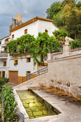 Fountain with drinking fountain for beasts in La Iruela, Cazorla, with the castle looming above the houses. photo