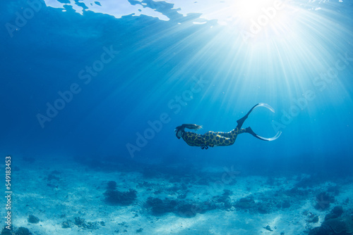 Women having fun underwater snorkeling in shallow clear waters with sunrays in the ocean