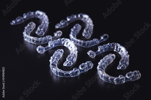 lot of aligners lie on a black background, studio shot