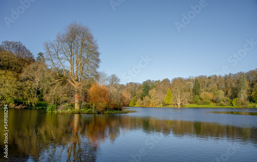 autumn afternoon sunshine illuminates woodland and the island in the lake, Stourhead estate Wiltshire UK