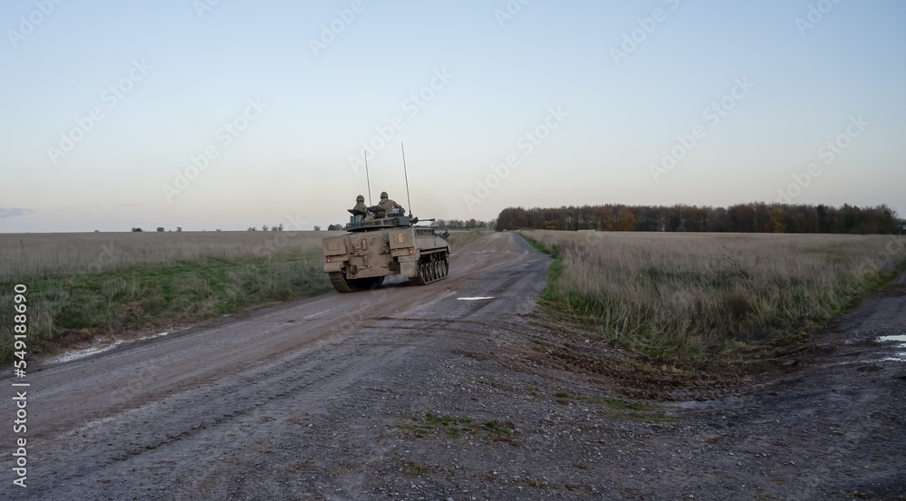 Fototapeta premium British army Warrior FV510 Fighting Vehicle in action driving on a mud track on a military battle exercise, Wiltshire UK
