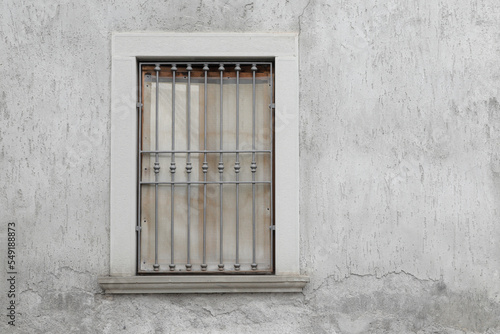 Grey  stone houswall with closed window, metal bars and white curtains, space for tesxt photo