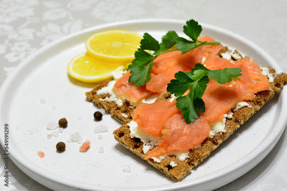 crisp bread with soft cheese and slices of salmon, decorated with parsley and lemon slices crisp bread with soft cheese and slices of salmon, decorated with parsley and lemon slices