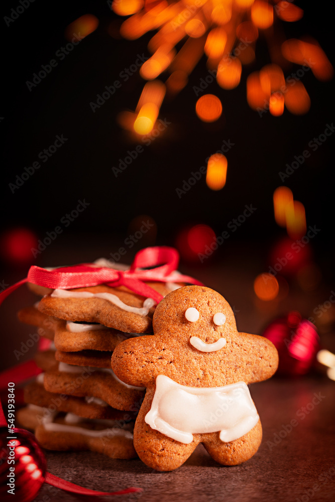 Homemade baked sweet and spicy gingerbread cookies in form of man and stars flavored with ginger, cloves and cinnamon served at festive Christmassy table with sparkling bokeh lights at Christmas Eve