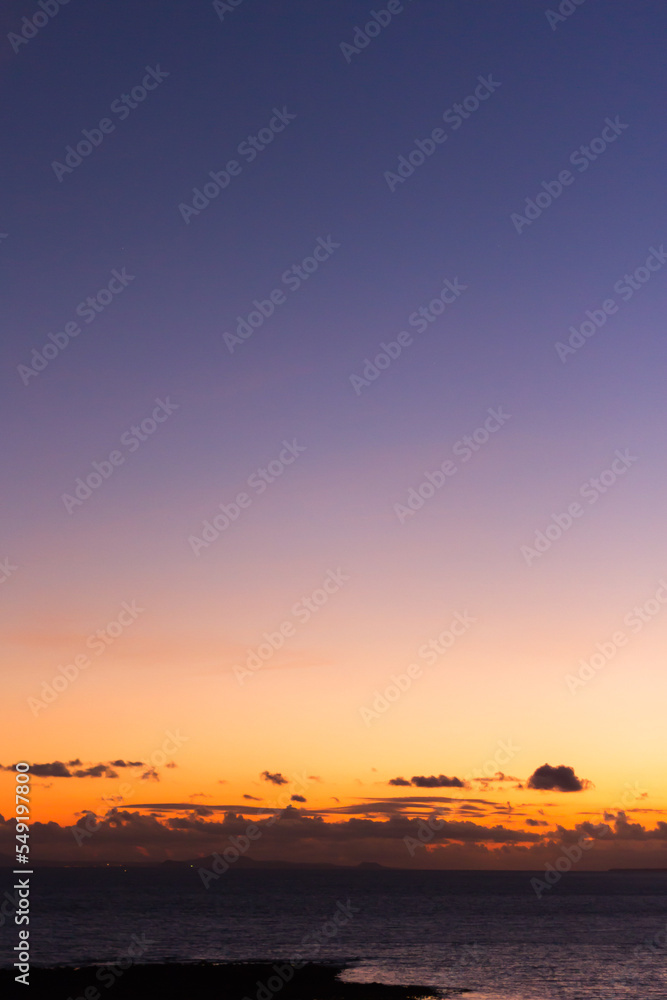 Orange and violet clouds in the darkness. Dark sea. Lanzarote, Canary Islands, Spain. Orange and violet clouds in the darkness. Dark sea. Lanzarote, Canary Islands, Spain.