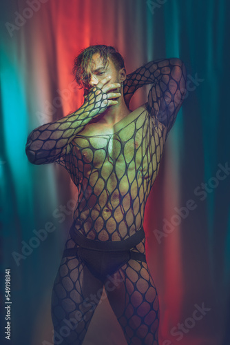 Multicolored creative artistic portrait of a sexy muscular young man with net outfit on a colorful rainbow lighting and background. photo
