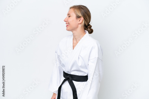 Young caucasian woman doing karate isolated on white background laughing in lateral position