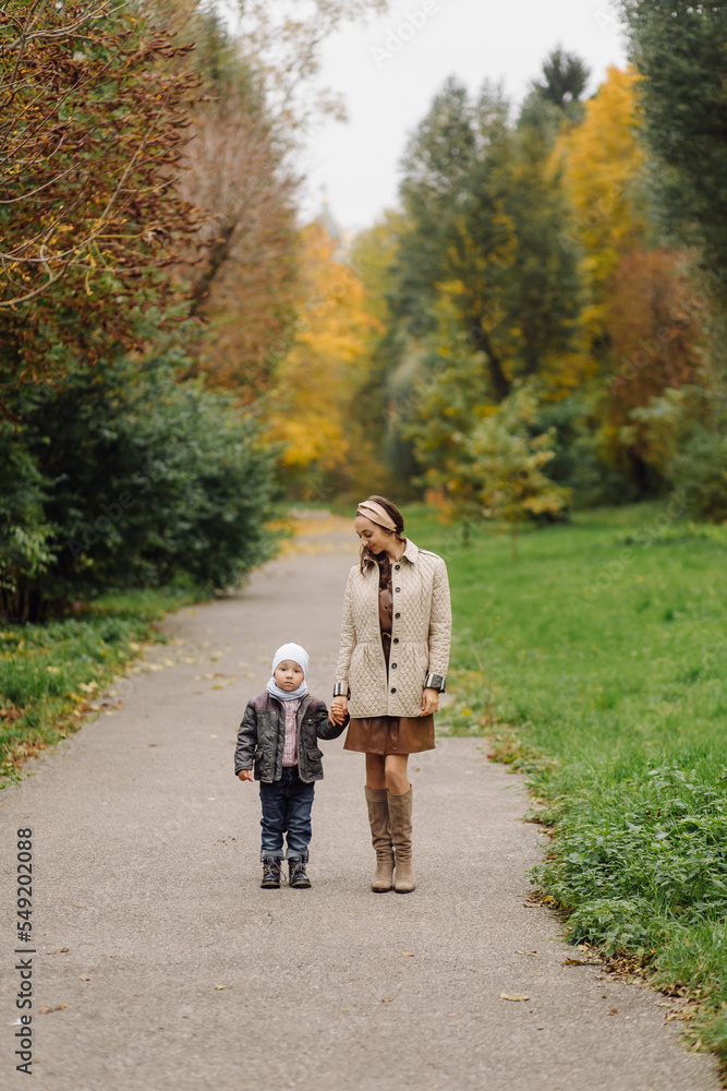 Fototapeta premium Mom and son walking and having fun together in the autumn park.