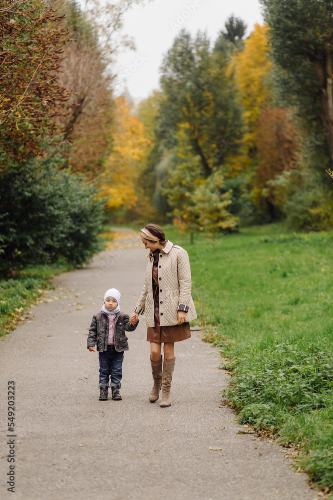 Fototapeta premium Mom and son walking and having fun together in the autumn park.