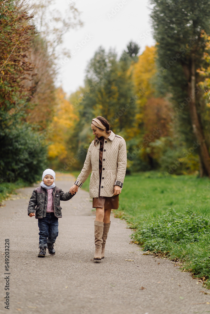 Fototapeta premium Mom and son walking and having fun together in the autumn park.