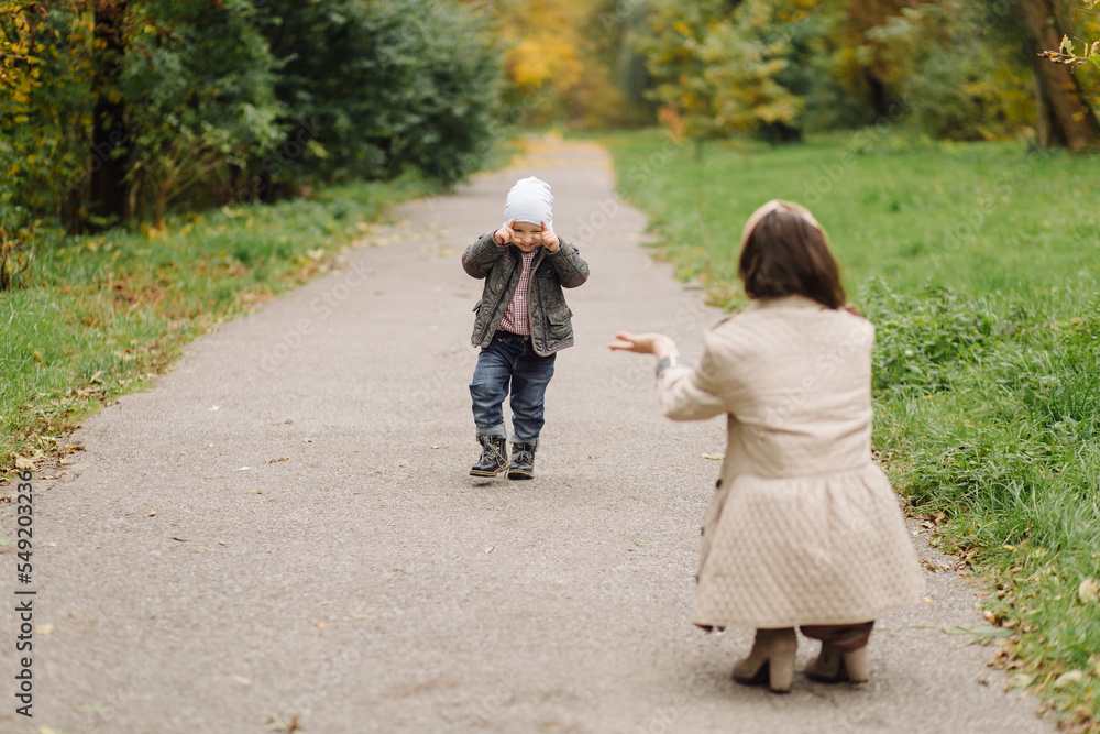 Fototapeta premium Mom and son walking and having fun together in the autumn park.