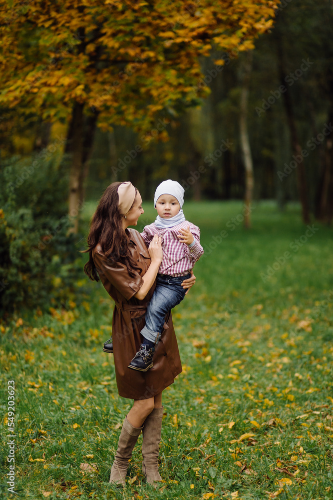 Fototapeta premium Mom and son walking and having fun together in the autumn park.