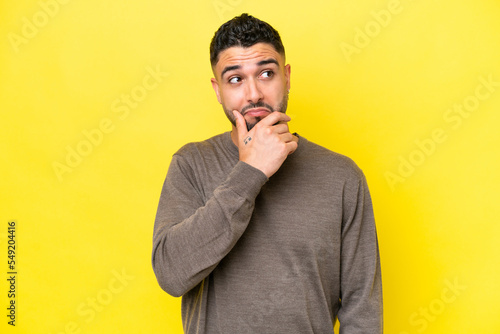 Young Arab handsome man isolated on yellow background having doubts and thinking